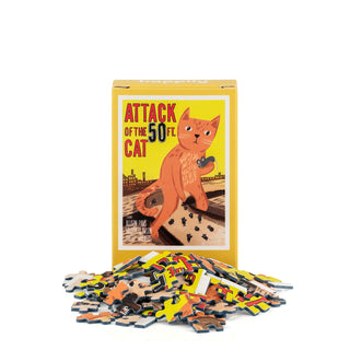 The Attack of the 50ft Cat | 99 Piece Mini Jigsaw Puzzle from Happily Jigsaw Puzzles features a box illustrated with a giant orange cat holding a car, with puzzle pieces displayed in front. Made from recycled board, this quirky mini jigsaw puzzle captures the playful spirit of a classic movie poster.
