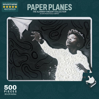 Paper Planes | 500 Piece Jigsaw Puzzle by Dope Pieces features Alannah Vincent's art of a boy reaching for a paper plane on a dark abstract background. Finished size: 24" x 28".