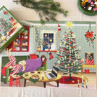 The ViSSEVASSE Lazy Days | 1,000 Piece Jigsaw Puzzle features a cozy living room scene with two people lounging on a couch surrounded by snacks, a laptop, and a decorated tree—crafted from FSC-certified materials for an eco-friendly holiday vibe.