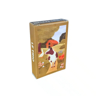 The Trevell Le Trio | 99 Piece Jigsaw Puzzle comes in a box adorned with artwork depicting a cow, a goose, and a red barn set amidst flowers and trees in a picturesque farm landscape, making it an enchanting choice for farm animal puzzle fans.