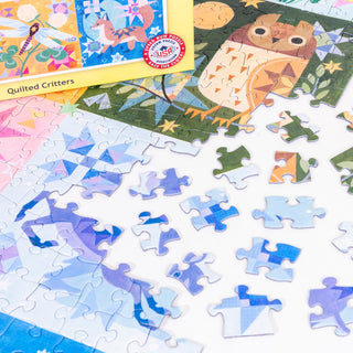 Partially completed Quilted Critters | 500 Piece Jigsaw Puzzle by PuzzleTwist, featuring quilt-style animal art with loose blue and white pieces scattered nearby.