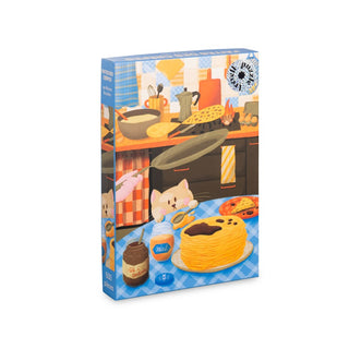 The Trevell Fantes Des Crêpes is a 500-piece eco-friendly jigsaw puzzle featuring a charming kitchen scene with a cat, pancakes, milk, chocolate spread, and utensils on a blue checkered tablecloth.