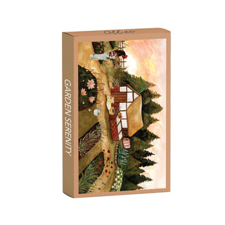 The Garden Serenity | 99 Piece Jigsaw Puzzle by Olleo Puzzles features a country house, garden path, flowers, and trees beneath a yellow and pink sky on its rectangular cottage-themed box.