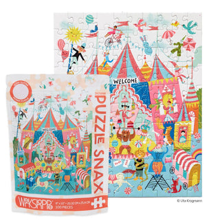 The WerkShoppe Colorful Circus 100 Piece Jigsaw Puzzle is assembled, with its vibrant box displayed in front, featuring acrobats, tents, animals, and performers.