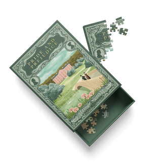 The Ohh Deer Pride and Prejudice | 99 Piece Jigsaw Puzzle makes a charming addition to any coffee table, featuring an open box that displays a scenic illustration by Andrew Kolb with partially assembled pieces both inside and beside the lid.