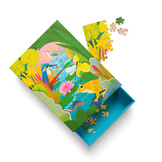The partially assembled Pond Life | 99 Piece Jigsaw Puzzle by Ohh Deer features vibrant nature-themed artwork by Natasha Durley, including a bird, frog, and flowers, with loose pieces and an open box.