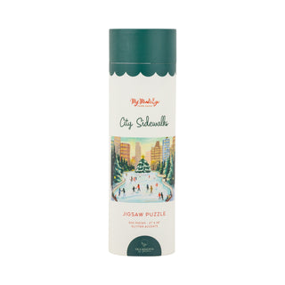 The City Sidewalks | 500 Piece Jigsaw Puzzle by My Mind’s Eye comes in a cylindrical box and features an illustration of people ice skating in a lively city park. This festive winter scene is brought to life with sparkling glitter accents, adding shimmer and charm to the delightful puzzle.