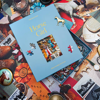 A box of the “Horse Girl | 1,000 Piece Jigsaw Puzzle” by Piecework Puzzles rests on a partially completed horse-themed puzzle, surrounded by horse-related items and vintage show photos.