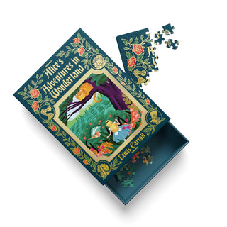 An Ohh Deer “Alice’s Adventures in Wonderland” 99 Piece Jigsaw Puzzle, featuring enchanting illustrations by Andrew Kolb, is displayed with its lid slightly open and several puzzle pieces scattered nearby.