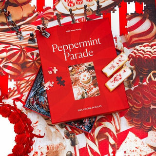 A Peppermint Parade | 1,000 Piece Jigsaw Puzzle by Piecework Puzzles is open on a candy-themed puzzle, with two decorated cookies on the Piecework Puzzles box.