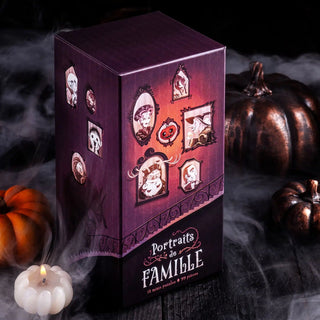 A Portraits de Famille Box Set from Trevell sits on a dark wooden surface, its illustrated family portraits puzzles surrounded by pumpkins, fog, and a lit candle—a perfect Halloween mini puzzle creation featuring 12 unique 99-piece puzzles.