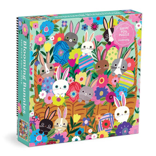 The Mudpuppy Blooming Bunnies 500 Piece Jigsaw Puzzle showcases vibrant illustrated rabbits, flowers, and patterned eggs, and includes dazzling foil accents on the front cover.