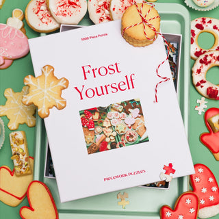 Piecework Puzzles’ "Frost Yourself | 1,000 Piece Jigsaw Puzzle" features a festive scene of holiday cookies on a green surface, creating the perfect challenge for puzzle and cookie lovers alike.