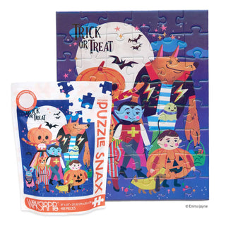Behind the packaging, which features a matching illustration, stands the completed WerkShoppe Trick or Treat | 48 Piece Jigsaw Puzzle, showcasing costumed children and playful monsters. Ideal for spooky season fun, this puzzle brings the festive Halloween spirit to life in every piece.