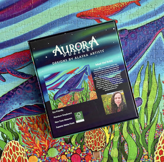 A box of Aurora Puzzles' Treasure Hunter 1,000 piece jigsaw puzzle is placed atop the completed, colorful marine life scene.