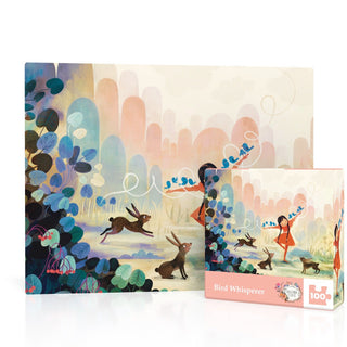The Bird Whisperer Mini 100 Piece Jigsaw Puzzle by New York Puzzle Company features a whimsical scene of a girl in an orange coat with birds, rabbits, and lush foliage. Made in the USA.