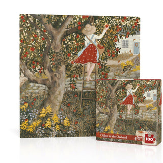A woman in a red skirt and hat picks apples on a ladder in an orchard, as shown on the box of the Oldest in the Orchard Mini 100 Piece Jigsaw Puzzle by New York Puzzle Company, made in the USA.
