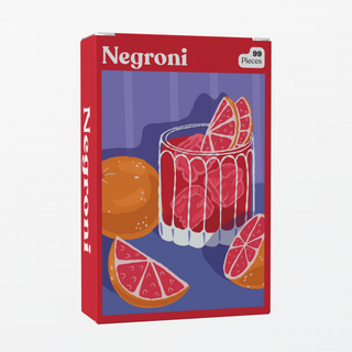 Puzzledly’s Negroni | 99 Piece Jigsaw Puzzle is a pocket-sized box featuring ribbon-cut pieces that form a vibrant illustration of a Negroni cocktail with orange slices on a table, set against a purple background.