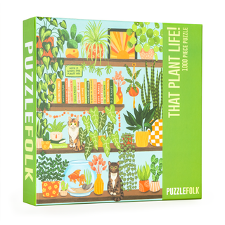 The That Plant Life! 1,000 Piece Jigsaw Puzzle by Puzzlefolk features illustrated shelves filled with houseplants, books, and two cats, packaged in a box labeled “Puzzlefolk” and “That Plant Life!”.