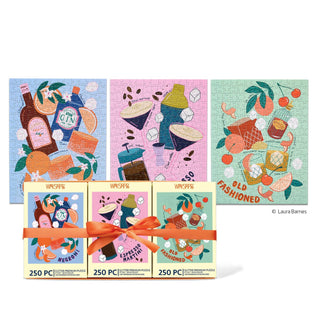 The WerkShoppe Cocktail Classics | 250 Piece Jigsaw Puzzle Set includes three vibrant puzzles showcasing illustrations of classic cocktails and their ingredients, each completed puzzle displayed above its matching box and all tied together with an orange ribbon—making a perfect gift.