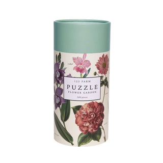 The Flower Garden | 500 Piece Jigsaw Puzzle by 123 Farm comes in a cylindrical box and features beautiful illustrations of various flowers.