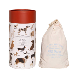 The Dogs | 500 Piece Jigsaw Puzzle by 123 Farm comes in a cylindrical illustrated box featuring dog breeds and includes a drawstring cloth bag labeled 123 Farm in light blue text.