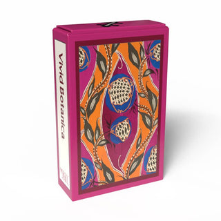 A magenta box labeled “Vivid Botanica | 99 Piece Jigsaw Puzzle” from Penny Puzzle showcases a vibrant botanical illustration with orange, pink, and blue patterns on the front, echoing E. A. Séguy’s iconic Art Deco style—perfect for fans of vintage mini puzzles.
