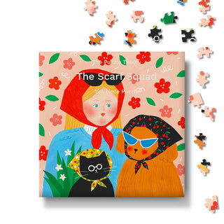 The Scarf Squad | 196 Piece Jigsaw Puzzle by The Puzzle Theory features a delightful illustration of a woman, a cat, and a dog all sporting headscarves, with scattered pieces displayed on a white background. Crafted from recycled paperboard, this charming and eco-friendly scarf puzzle is perfect for any puzzler.