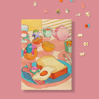 The Puzzle Theory’s “Breakfast Party | 500 Piece Jigsaw Puzzle” features a vibrant breakfast scene with eggs, toast, bacon, tea, and drinks on a pink background scattered with puzzle pieces.