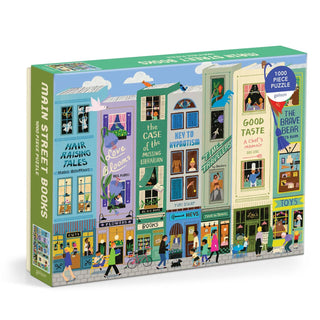 The Main Street Books 1,000 Piece Jigsaw Puzzle by Galison features vibrant book-shaped storefronts, lively scenes of people and animals, and charming nods to literary genres throughout a whimsical street illustration.