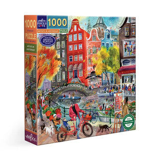 The eeBoo Artists in Amsterdam 1,000 Piece Jigsaw Puzzle showcases a lively city scene with people, bikes, dogs, and colorful canal-side buildings—ideal for fans of the Amsterdam or Artist Cities puzzle collections.