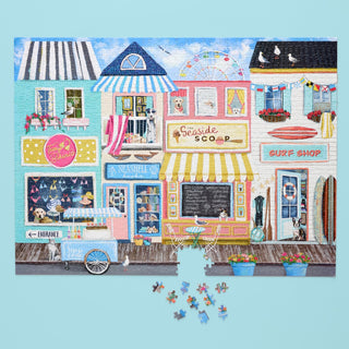 The WerkShoppe Beach Boardwalk | 1,000 Piece Jigsaw Puzzle is partially completed, with several pieces scattered below on a light blue background.