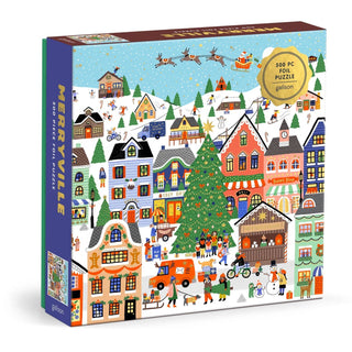 The Merryville | 500 Piece Jigsaw Puzzle by Galison features a beautifully illustrated winter village scene with snow, decorated houses, a large Christmas tree, and festive activities—all brought to life with Holly Maguire’s vibrant artwork.
