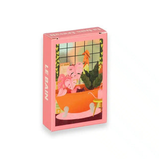 The Le Bain | 99 Piece Jigsaw Puzzle by Trevell comes in a pink rectangular box with a vivid bathtub, houseplants, and window illustration—ideal for fans of illustrated or mini puzzles.