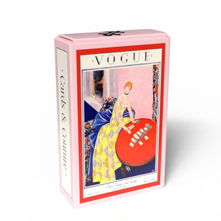 The Cards & Couture 99 piece jigsaw puzzle by Penny Puzzle features a pink box with a vintage Vogue cover illustration: a woman in a gown at a red card table, capturing the allure of classic fashion magazines.
