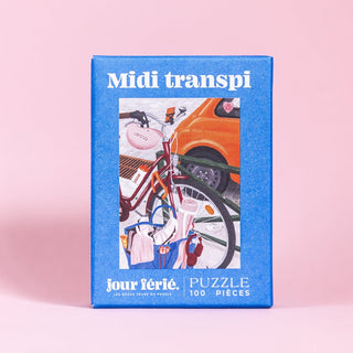 A blue box labeled Midi Transpi | 100 Piece Jigsaw Puzzle by Jour Férié features a bike and orange car; ribbon cut and made in France.