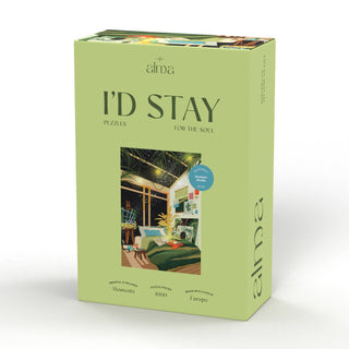 A green Alma Puzzles box titled "I'd Stay" features a cozy bedroom scene. This 1,000-piece jigsaw puzzle, labeled as a cozy interiors puzzle, is made with love in Europe.