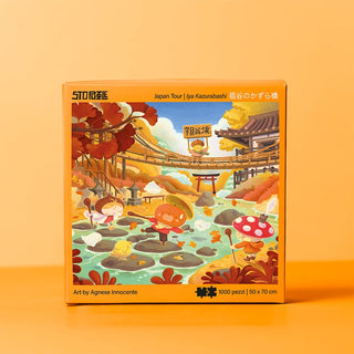 StoPuzzle's Japan Tour | 1,000 Piece Jigsaw Puzzle features cartoon characters exploring a Japanese garden with a bridge, trees, water, and traditional buildings. Showcases Iya Valley’s charm. Size: 50 x 70 cm.