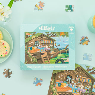 The Treetop Hideout | 250 Piece Jigsaw Puzzle by Villager Puzzles features a cozy cabin scene, with scattered pieces, cookies, and a drink nearby—an ideal pick for Canadian puzzle fans.