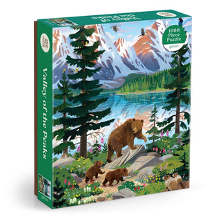 Enjoy assembling the "Valley of the Peaks | 1,000 Piece Jigsaw Puzzle" by Galison, featuring a breathtaking nature scene of a mountain landscape with a bear and three cubs strolling beside a tranquil lake, all framed by trees, birds, and snow-capped peaks. This captivating puzzle is perfect for wildlife and scenery enthusiasts alike.