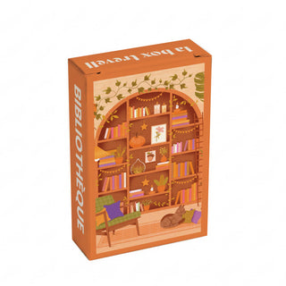 Here’s a rewritten version using your product data: The Trevell Bibliothèque | 99 Piece Jigsaw Puzzle comes in a box adorned with “BIBLIOTHÈQUE” on the side, showcasing an illustrated bookshelf, thriving plants, a cozy chair, and a cat lounging contentedly on the floor. This charming puzzle supports 1% for the Planet and promises delightful afternoons with its perfectly sized finished design.