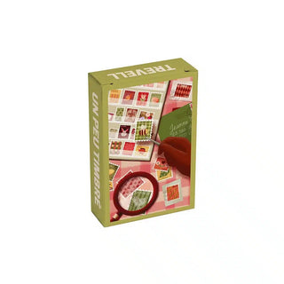 Un Peu Timbré 99 Piece Jigsaw Puzzle box showing a hand using a magnifying glass to inspect an assortment of vintage postage stamps.