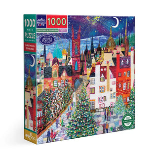 The eeBoo Christmas in Edinburgh | 1,000 Piece Jigsaw Puzzle features Nikki Monaghan’s festive winter cityscape with vibrant buildings, a large Christmas tree, and a starry night—perfect for Scotland puzzle fans.