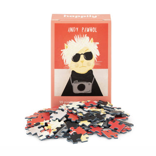 The Andy Pawhol | 99 Piece Mini Jigsaw Puzzle by Happily Jigsaw Puzzles features a whimsical cat dressed as Andy Warhol with sunglasses and a camera, made from recycled board and displayed with its pieces in front of the box.