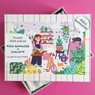 The La Serre Aux Chats 1,000 Piece Jigsaw Puzzle by Pièce Rapportée features an illustrated woman arranging plants in a cozy room with several cats, surrounded by potted plants and gardening tools.