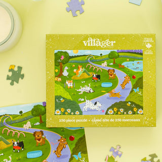 The Bark Park | 250 Piece Jigsaw Puzzle by Villager Puzzles features an illustrated park scene with animals, displayed on a light yellow surface—an ideal gift for dog lovers.