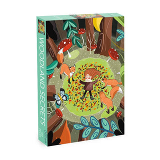 The vibrant design of Olleo Puzzles’ Woodland Secrets | 500 Piece Jigsaw Puzzle captures a girl resting on forest leaves amidst three foxes, mushrooms, plants, and a butterfly—an enchanting scene inspired by the book cover that invites you to piece together nature’s hidden wonders.