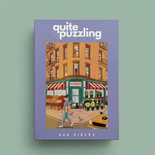 The Quite Puzzling "Corner Market" 500-piece jigsaw puzzle features an illustrated street corner with a market, flowers, a dog walker, and a taxi—perfect for New York puzzle enthusiasts.