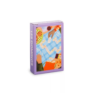 The Trevell Les Dominos 99 Piece Jigsaw Puzzle comes in a purple box featuring an illustration of people playing dominoes at a blue checkered table, surrounded by snacks and drinks.