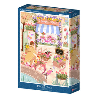 The Flower Bikes | 500 Piece Jigsaw Puzzle by Pieces & Peace, made in France, features a vibrant springtime scene of a flower shop with bikes, blooming flowers, and people walking.